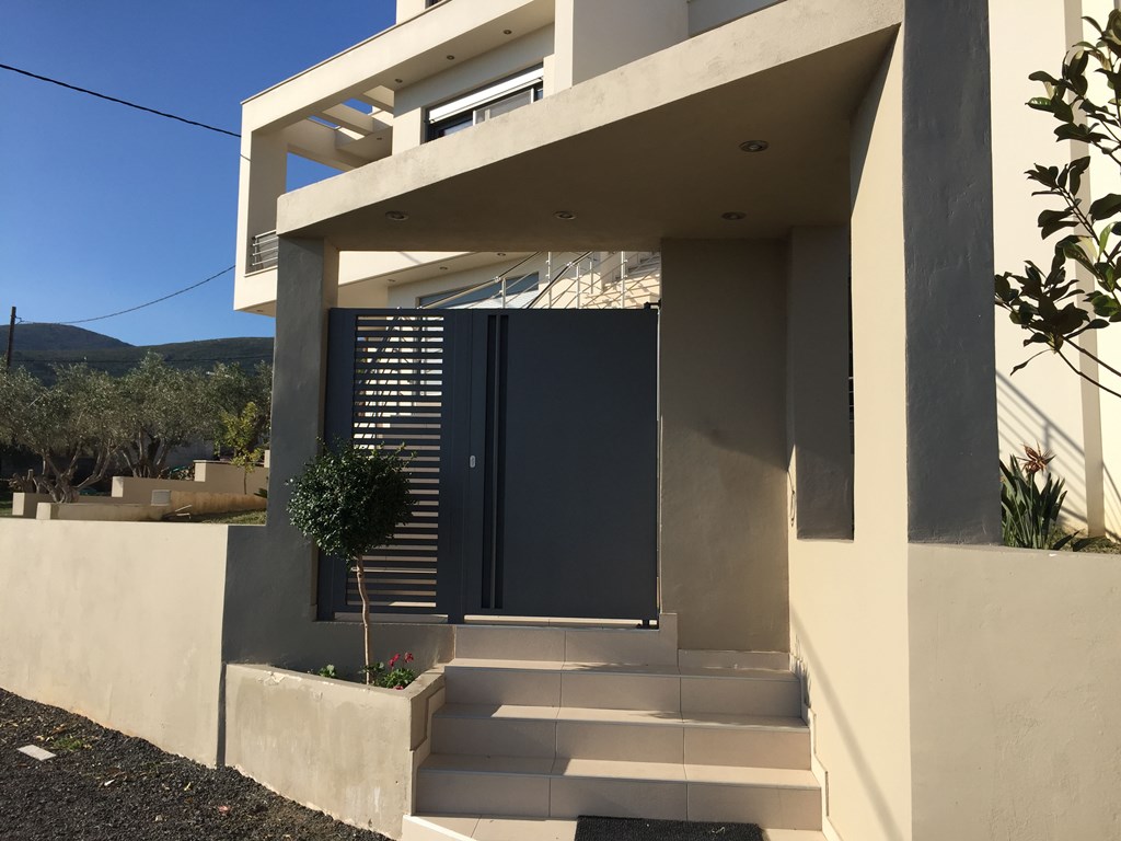 Αυλόπορτα μεταλλική από λαμαρίνα 'τυφλή' και σταθερό τμήμα με μεταλλικά οριζόντια προφίλ.